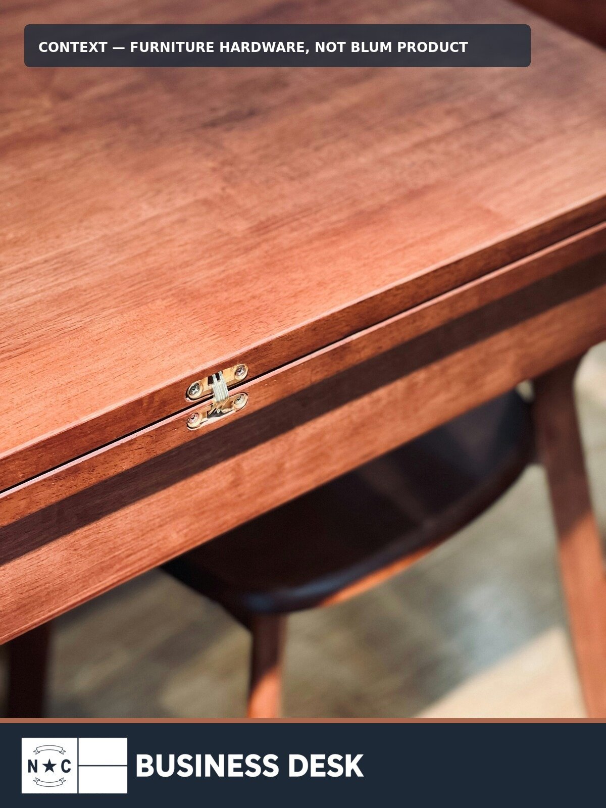 Contextual photograph of furniture hardware on a wooden drawer, explicitly labeled as not a Blum product, above the NC Business Desk footer.