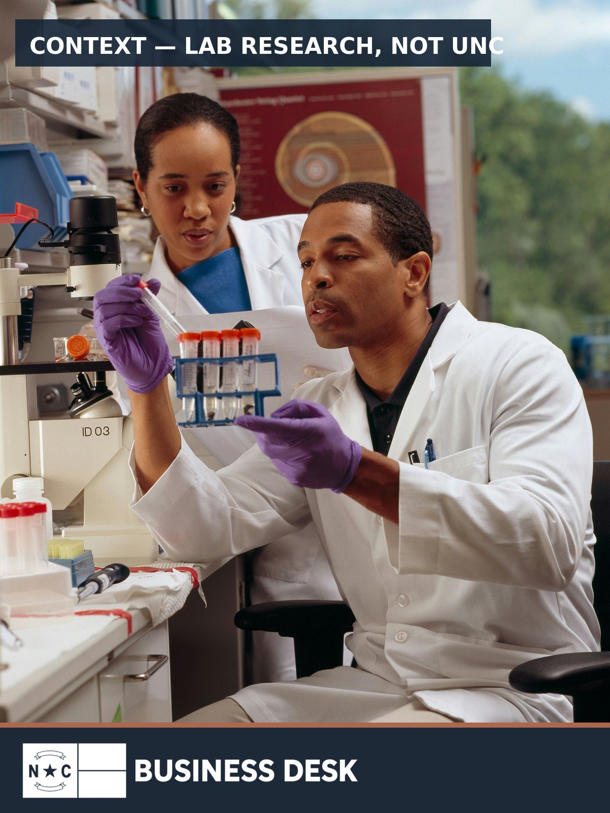 Two laboratory researchers examine test tubes; contextual image, not UNC or UNC Lineberger.