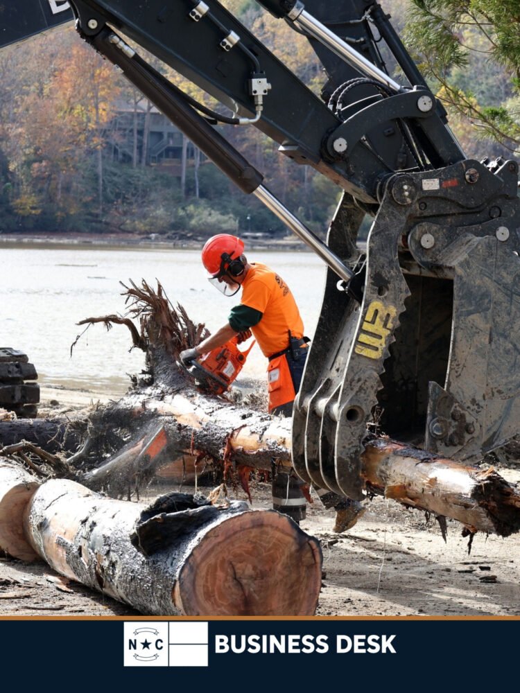 A U.S. Army Corps of Engineers contractor cuts storm debris beside heavy equipment in Lake Lure, North Carolina.