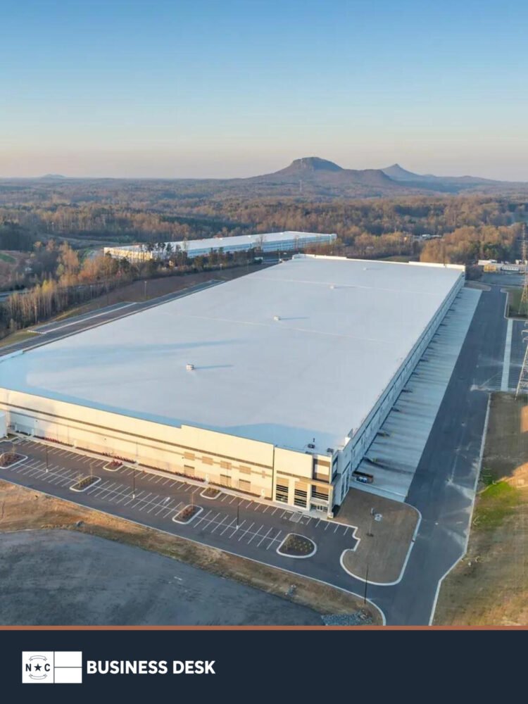 Aerial view of the 1500 Delta Drive distribution center in Gastonia with Crowders Mountain in the distance and the approved NC Business Desk footer.