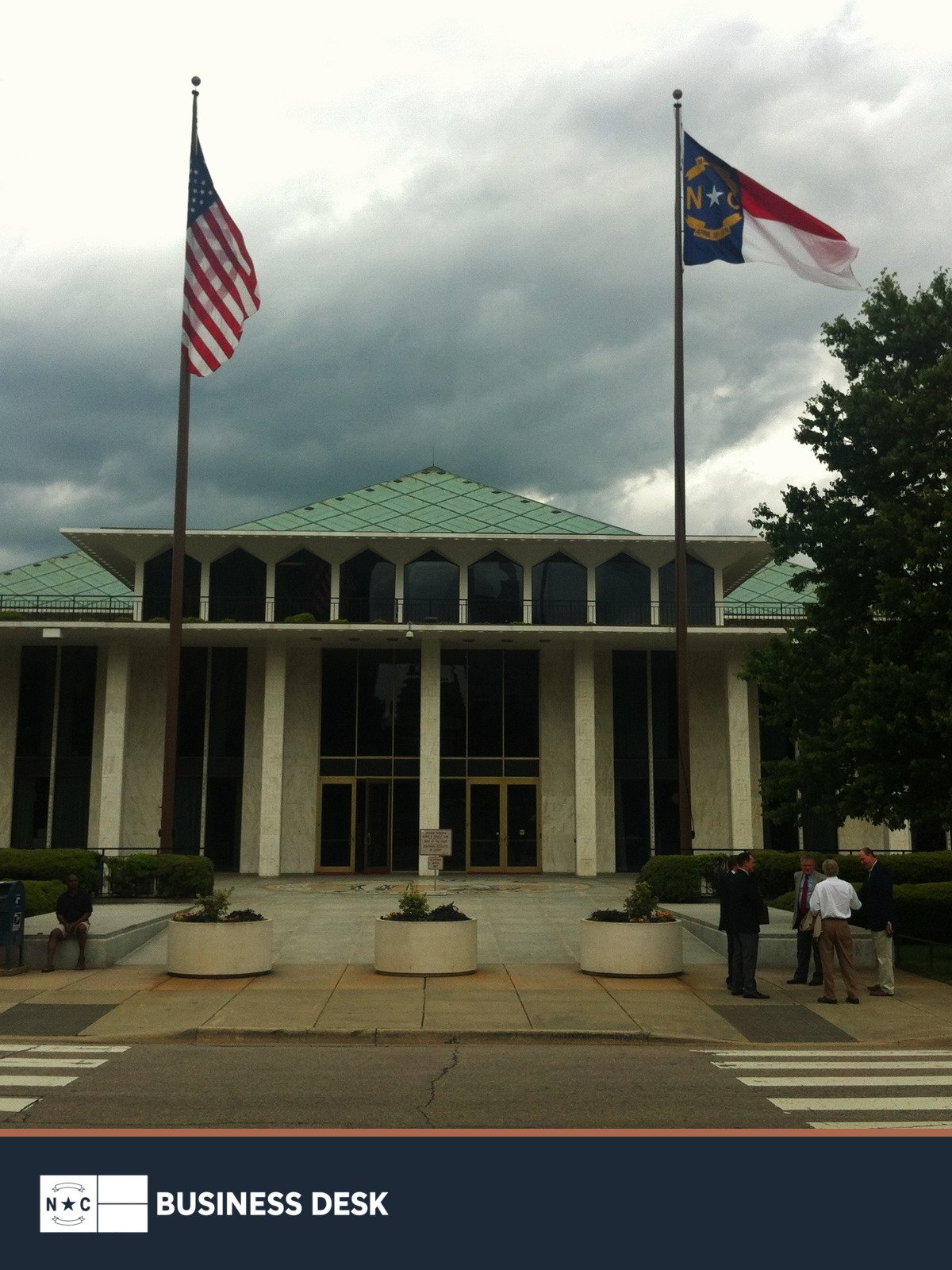North Carolina Legislative Building in Raleigh with the U.S. and North Carolina flags above the NC Business Desk footer.