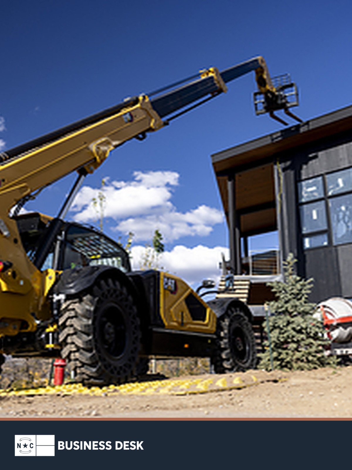 Cat telehandler at a construction site above the NC Business Desk footer.