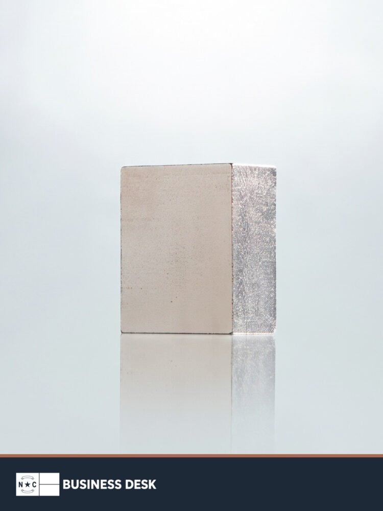 A single rare-earth magnet photographed by Vulcan Elements above the NC Business Desk footer.