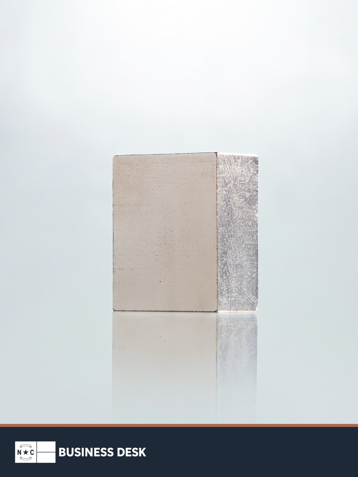 A single rare-earth magnet photographed by Vulcan Elements above the NC Business Desk footer.