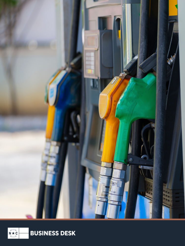 Colorful fuel nozzles at a gasoline pump above the NC Business Desk footer.